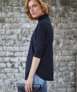 Model waerinf WInster loose fit polo neck top and jeans holding the Derby clutch bag in hand